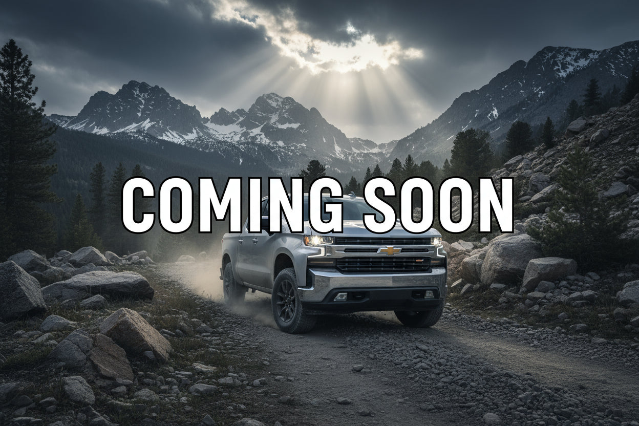 Black truck driving through water on a beach with trees in the background
